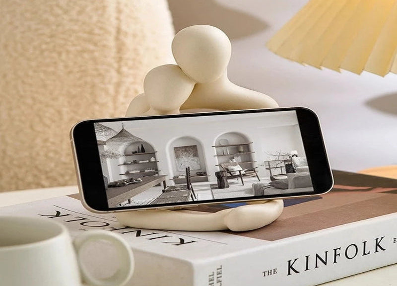 Phone stand with a phone on top of it, placed on a book with 'The Kinfolk' title.